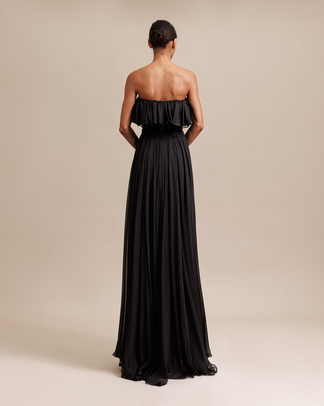 The back of a strapless cut flared chiffon long evening dress with ruffles on the bust and draping details.