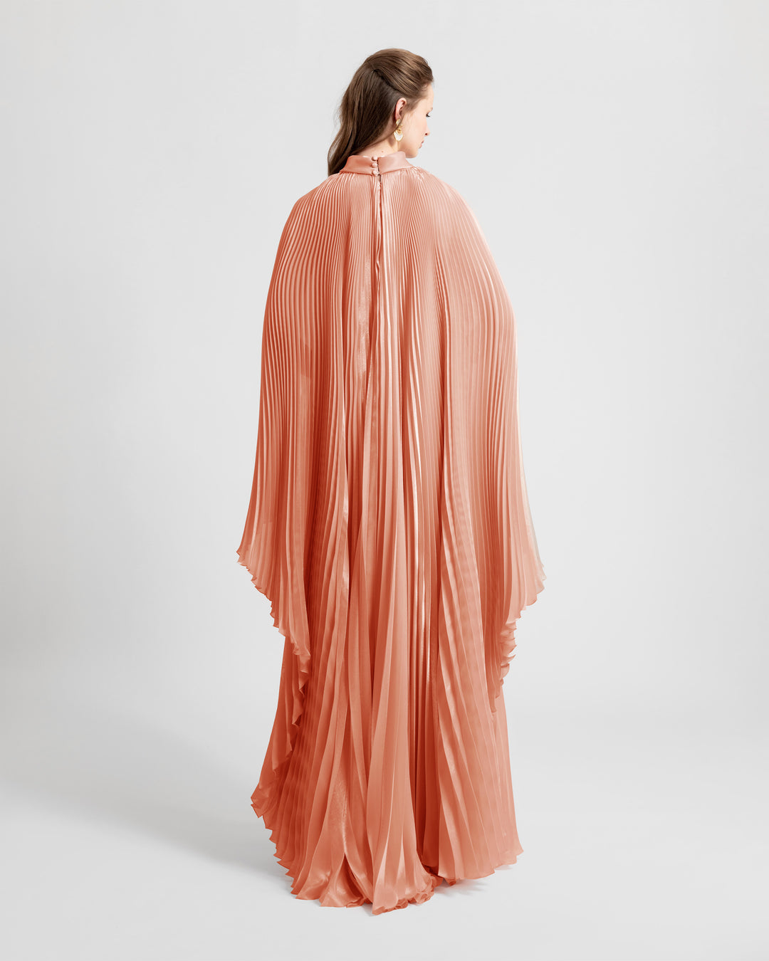 The back of a fully pleated soft lame organza flared dress with cape-like sleeves.