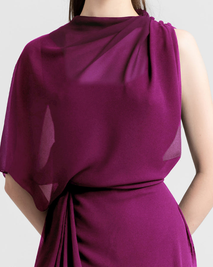 A close-up of an asymmetrical chiffon evening dress with draping details featuring a slit on the side.