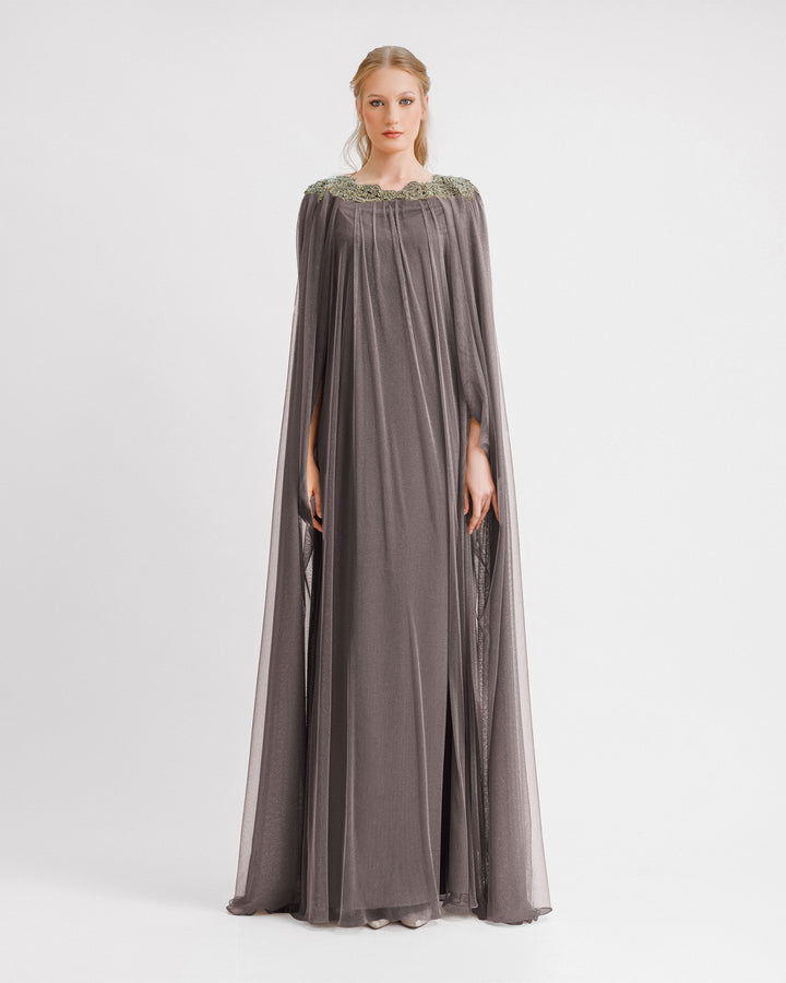 A loose-cut kaftan grey evening dress with beadings at the neckline and floor length cape like sleeves.