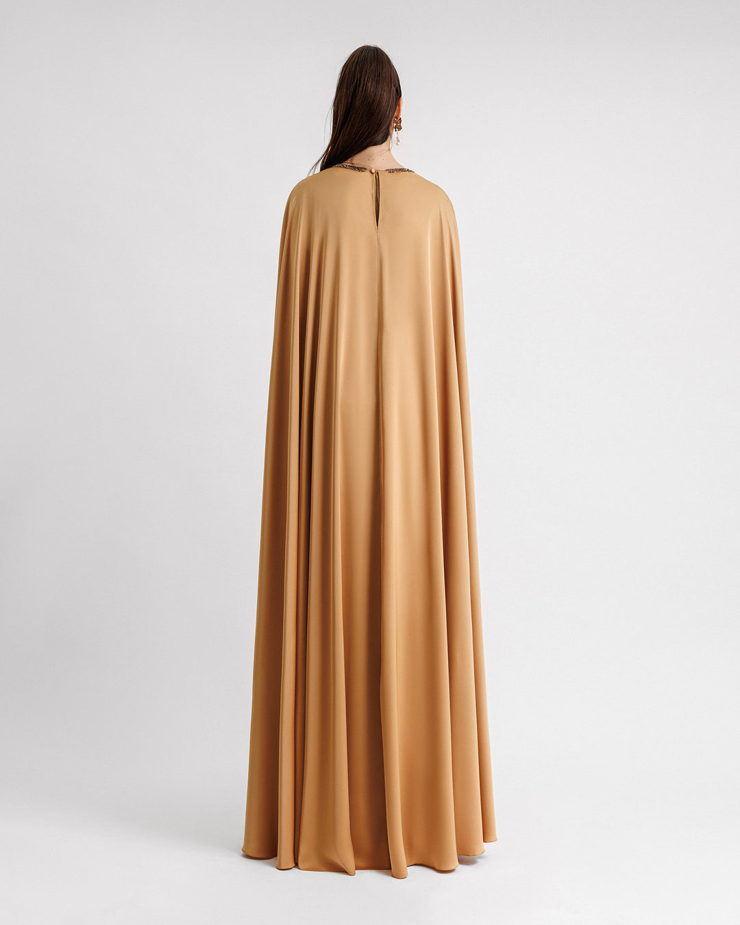 The back of a caramel color kaftan-style evening dress with a beaded neckline.