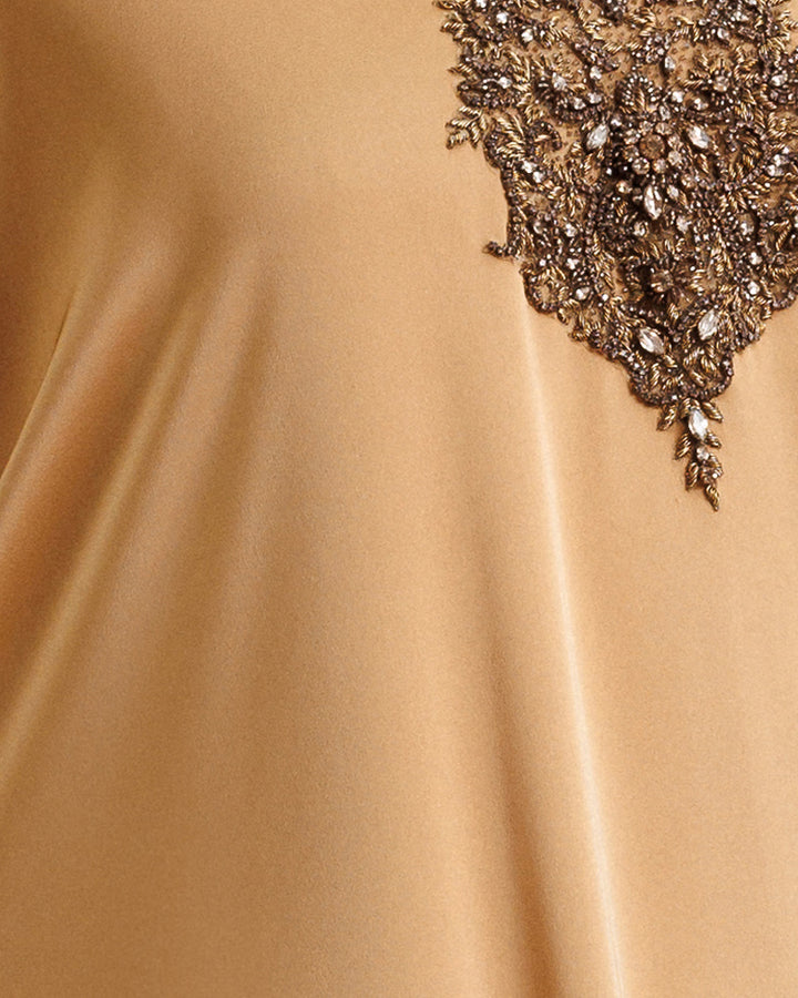 A close-up of a caramel color satin fabric with embroidery.