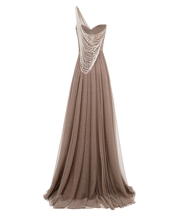 The back of a one-shoulder draped shiny tulle dress in taupe color featuring an asymmetrical tasseled back.