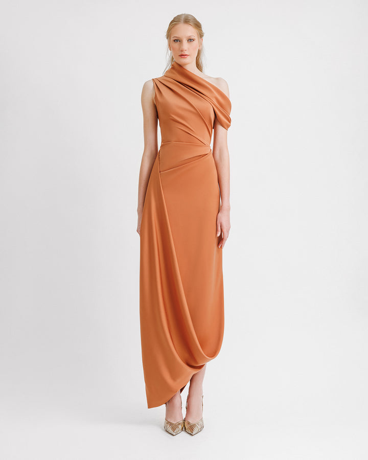 A draped copper evening dress featuring an asymmetrical neckline and hemline, and a slit on the side.