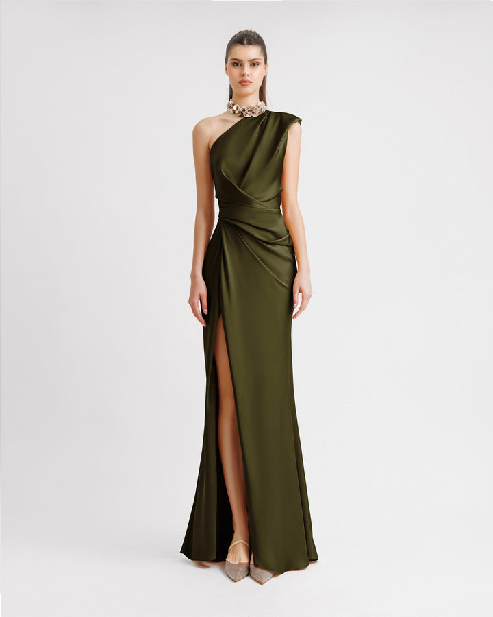 A one-shoulder draped satin evening dress in olive green with floral embellishments on the neckline and an open slit on the side.