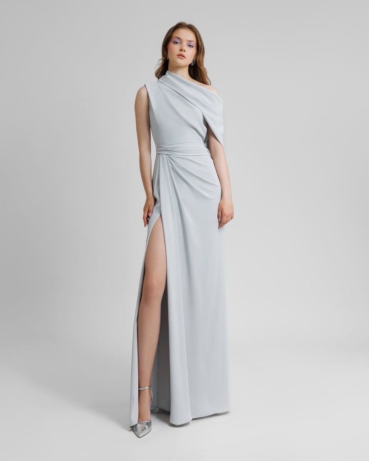 An asymmetrical off shoulders neckline long grey evening dress with draping details and a high slit on the side.