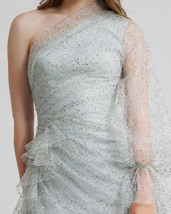 A close-up of a one shoulder grey evening dress with draping details, and a puffed see-through sleeve.