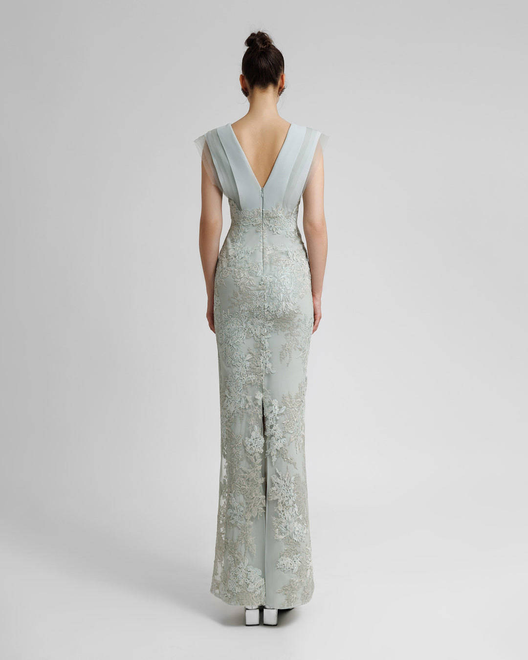 The back of a fully embellished  V-shaped open back grey evening dress with a middle slit.