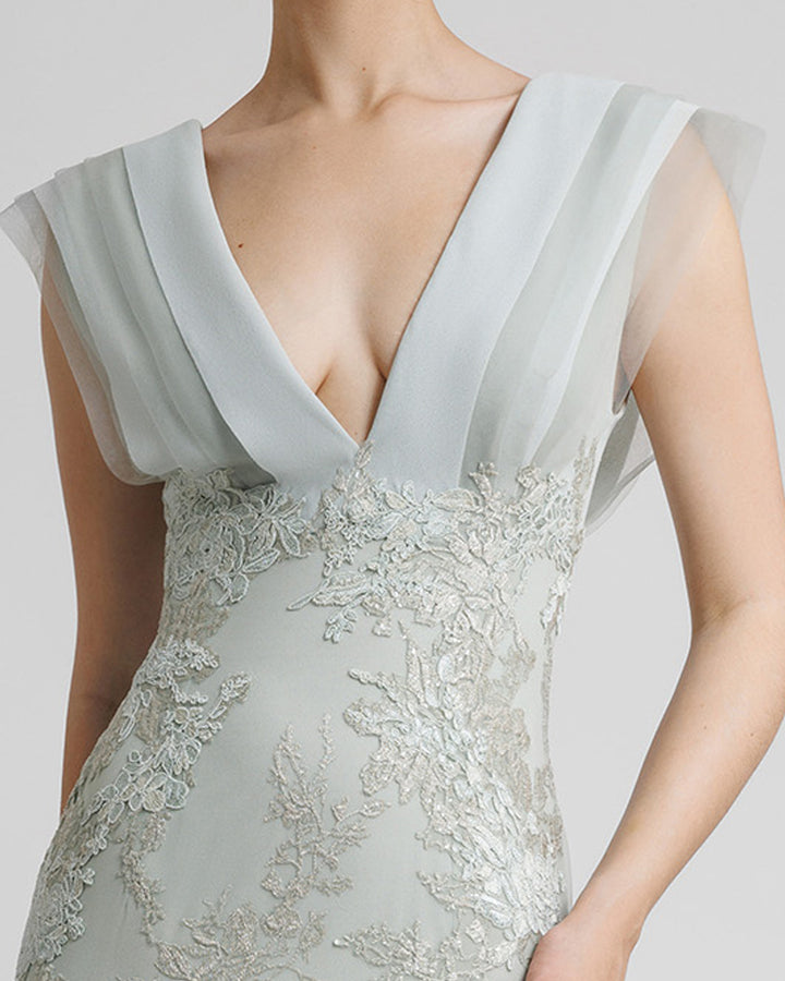 A close-up of a fully embellished deep V-shaped neckline grey evening dress with draping details on the bust.