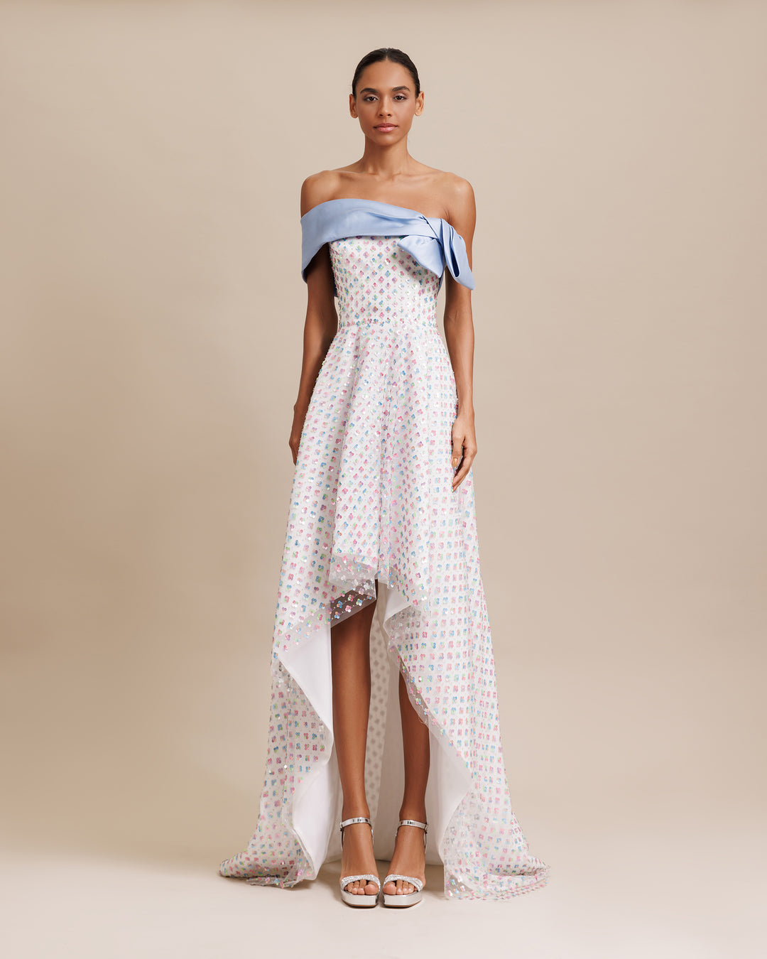 An off-shoulders cut neckline with blue mikado bow design, paired with multicolor sequined tulle lower part featuring an asymmetrical hemline.