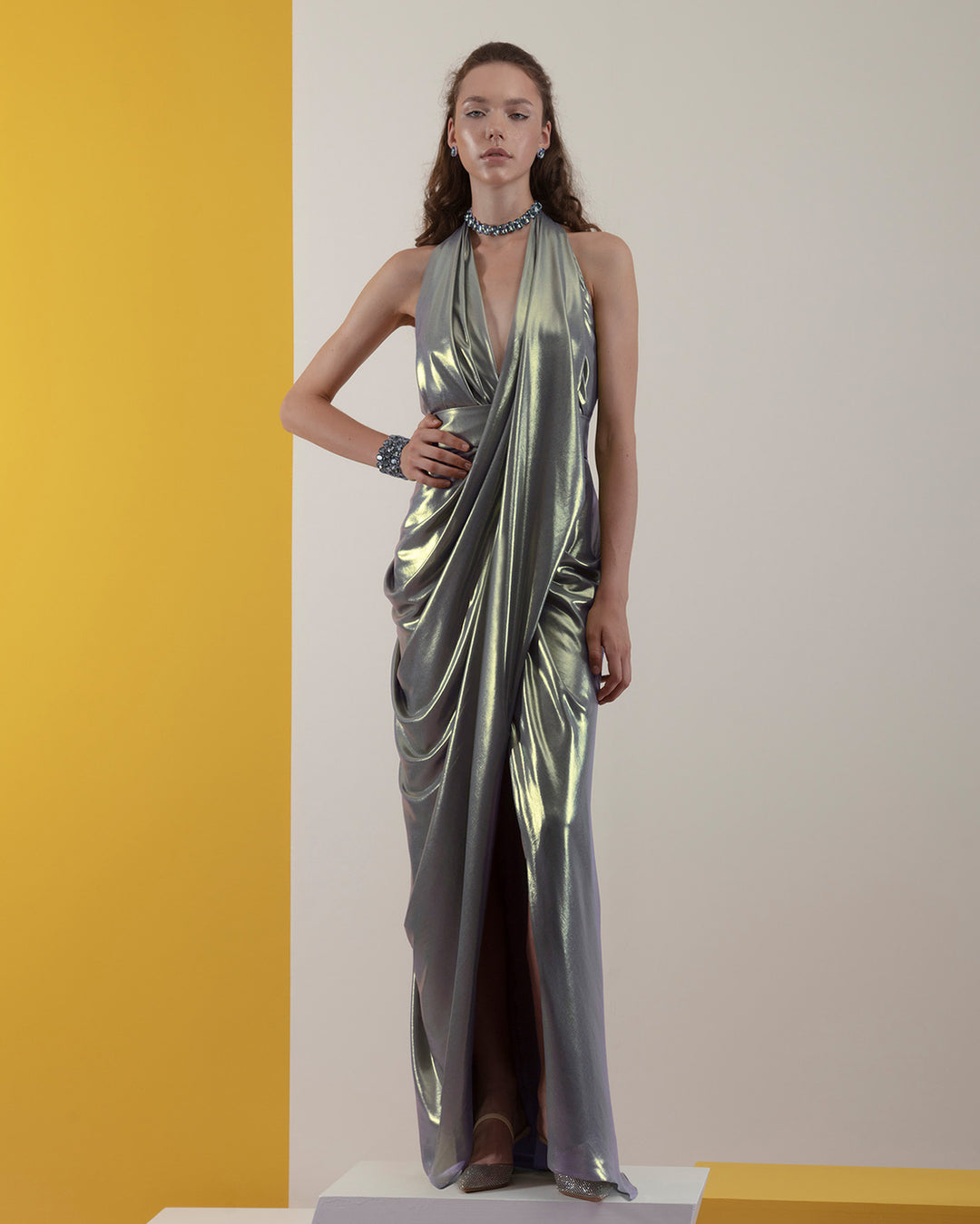 A deep V-neckline, draped details grey laminated chiffon long evening dress with backless design and an open slit in the front.