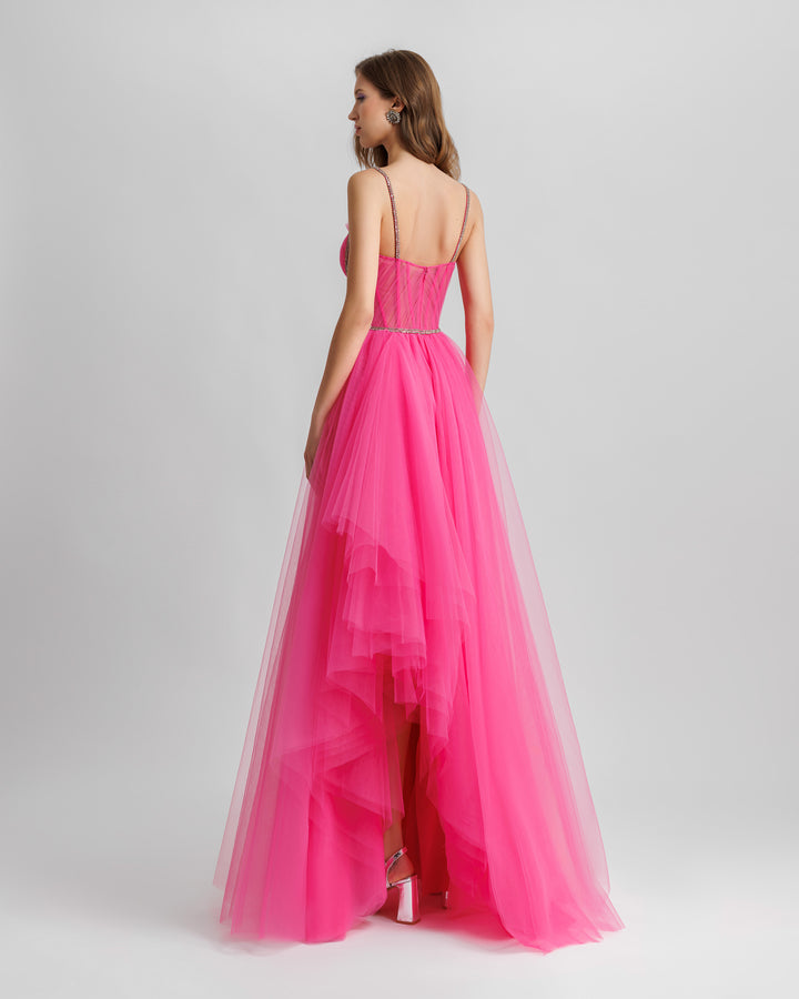 The back of a fuchsia tulle dress featuring beaded straps, a draped corset, and a ruffled slit on the back.