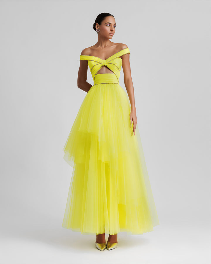 An off-the-shoulders evening yellow dress with beaded trimmings on the corset, a cut-out at the front, and an asymmetrical layered tulle skirt.