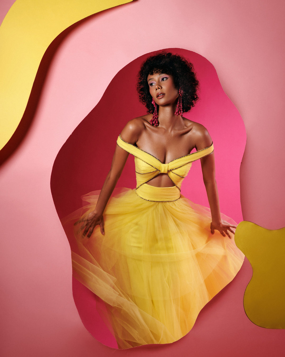 An off-the-shoulders evening yellow dress with beaded trimmings on the corset, a cut-out at the front, and an asymmetrical layered tulle skirt.