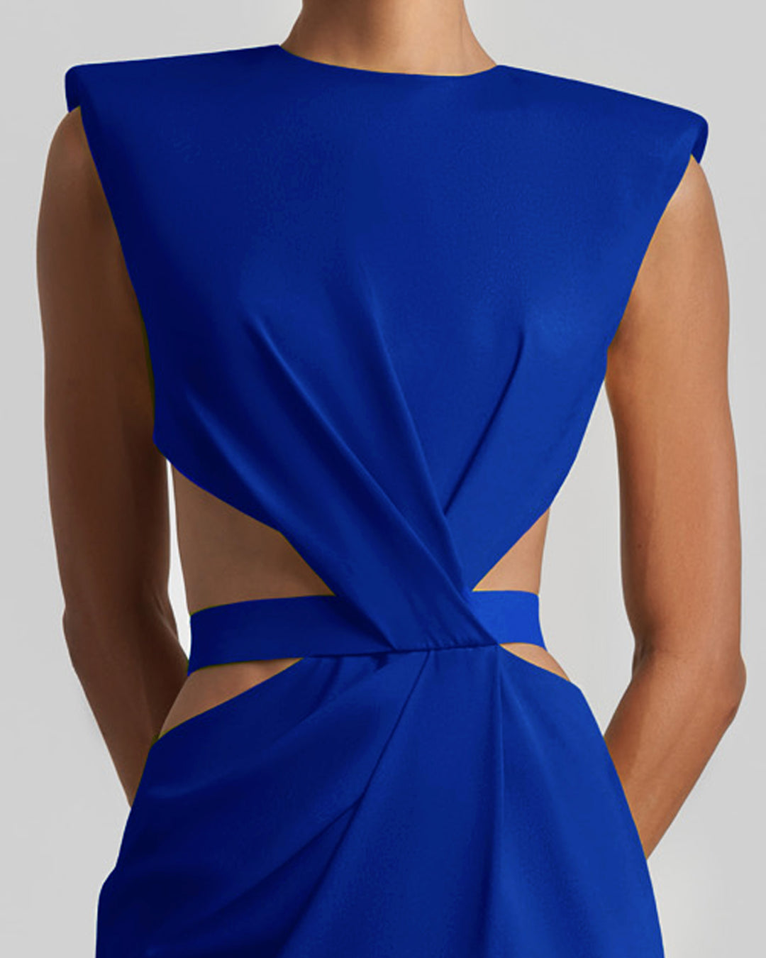 A close-up of a slim-cut royal blue evening dress featuring padded shoulders, draping, and cut-outs on the waist.