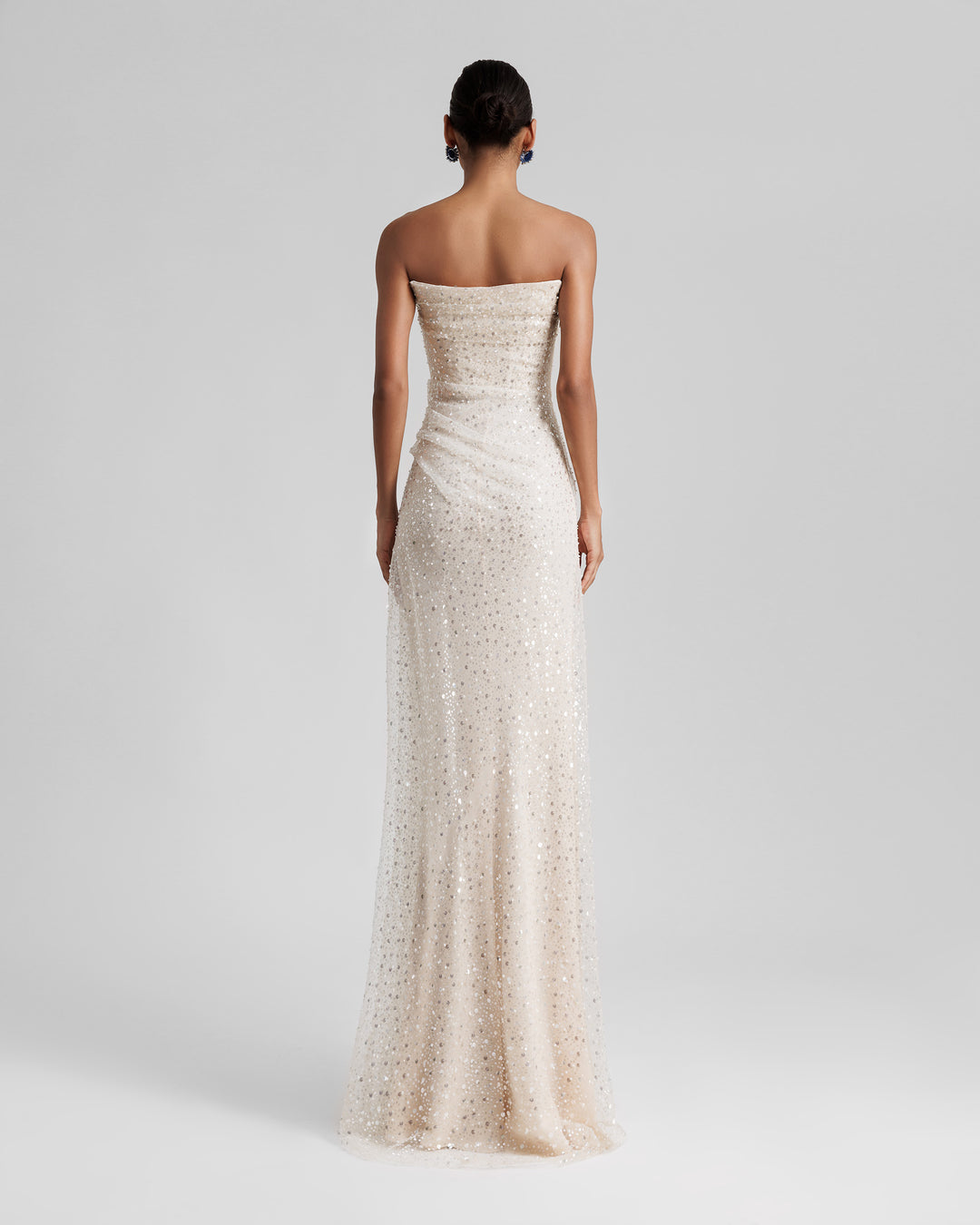 The back of a strapless A-line silhouette cream tulle evening dress with intricate embroidery and one sided waist draping.