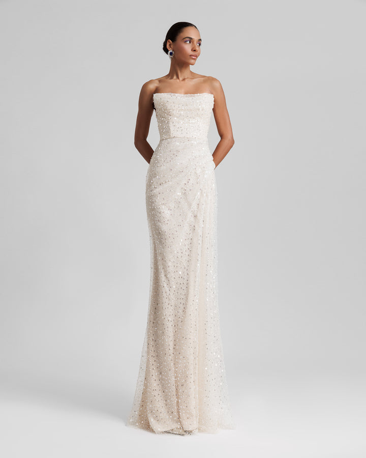 A strapless A-line silhouette cream tulle evening dress with intricate embroidery and one sided waist draping.