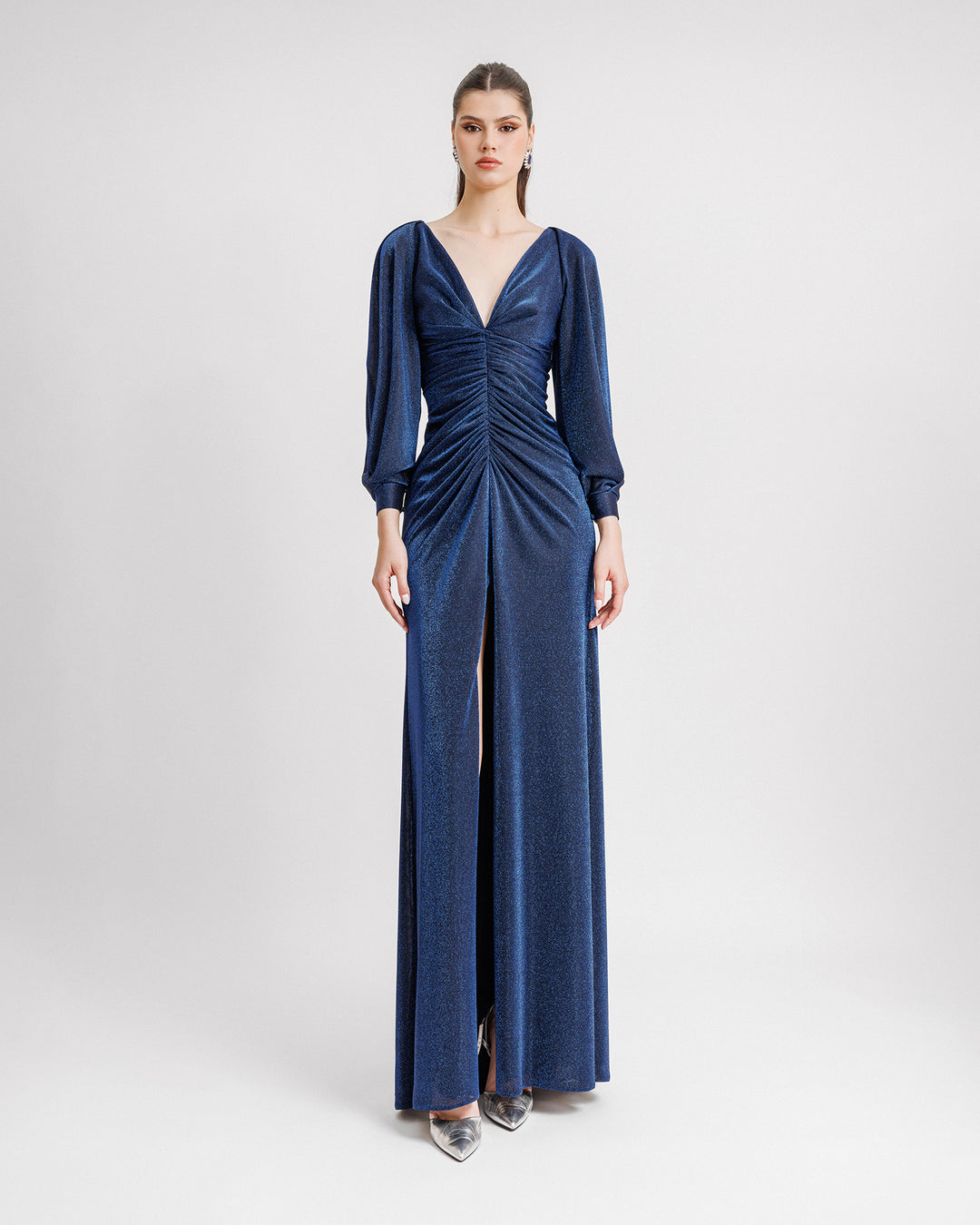 A V-neckline, long sleeves evening dress in midnight blue with a gathered bodice, and an open middle slit.