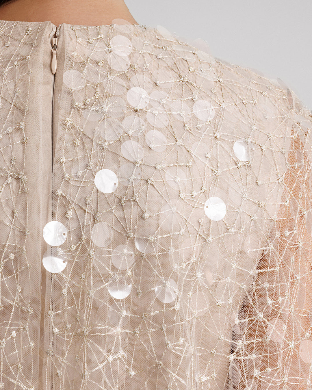 A close up of a fully beaded cape in sequins embroidered tulle.