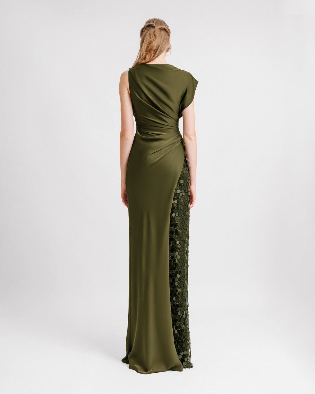 The back of an asymmetrical draped satin evening dress in olive green color with a slit on the side and a sequin side underskirt.