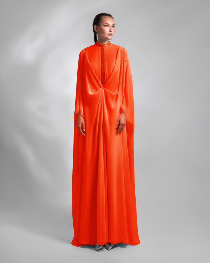 A loose long chiffon evening dress with draping and embellishment details.