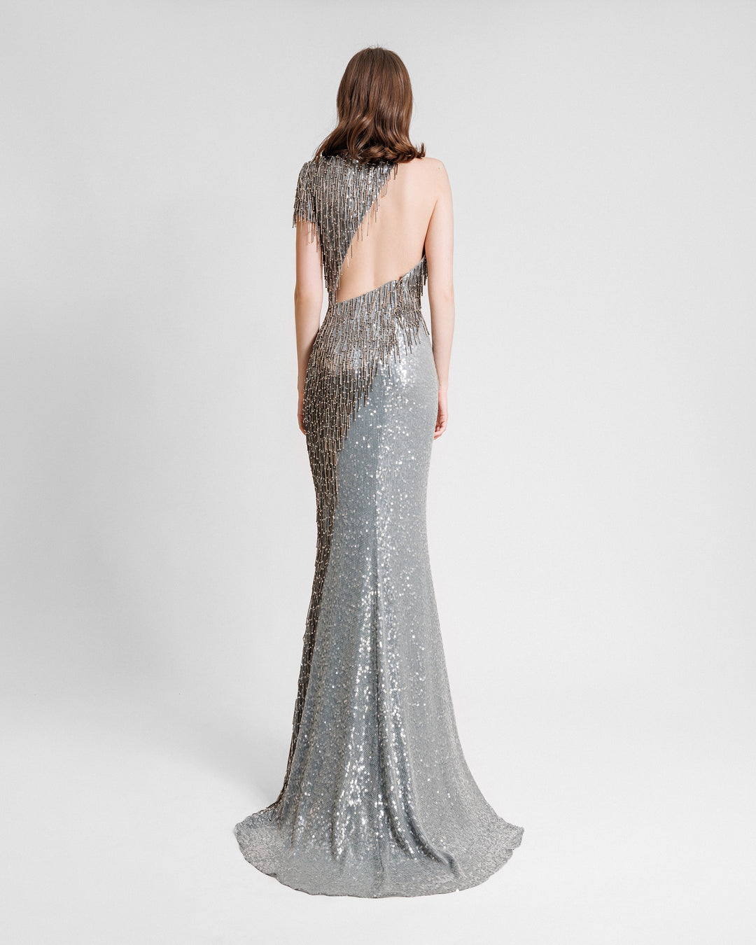 The back of a single short sleeve evening dress featuring beaded tassels and an asymmetrical back cut-out.