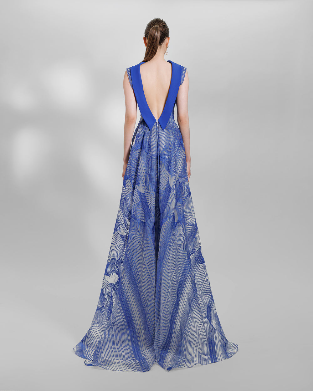 An open back of a royal blue slim-cut embroidered pattern dress with a high neck.