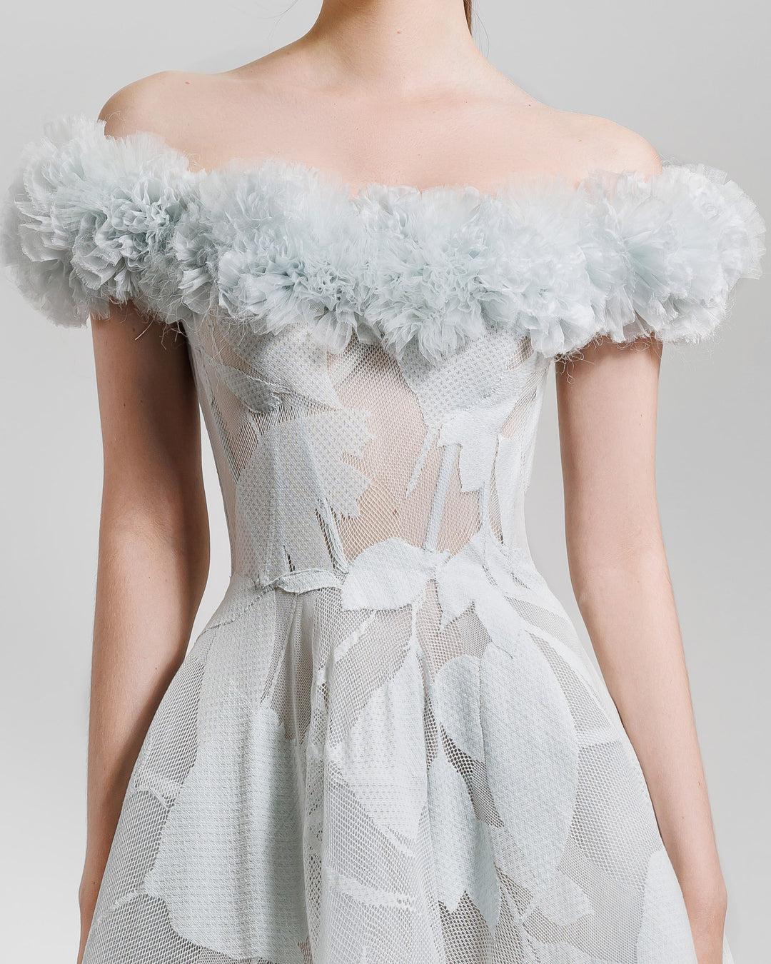 A close-up of a midi sheer patterned lace grey dress with off-the-shoulders rushed organza neckline, featuring a cage like flared skirt .