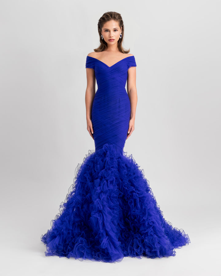 An off-the-shoulders draped mermaid-cut blue evening dress with rushed tulle at the bottom.