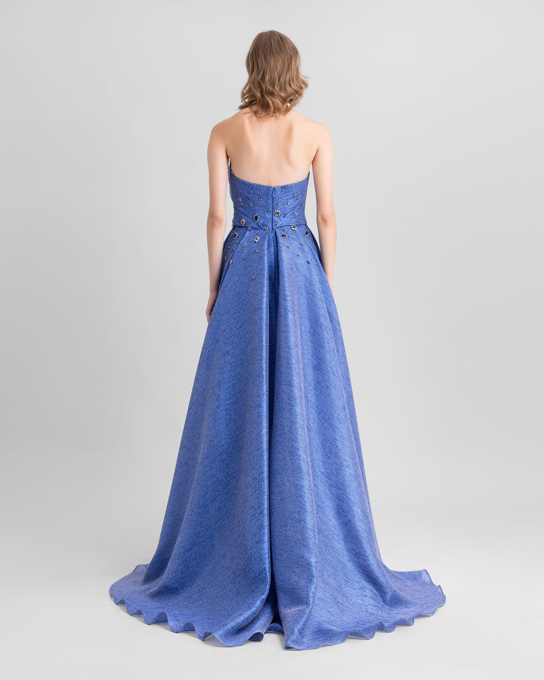 The back of a strapless draped blue evening dress with beadings.