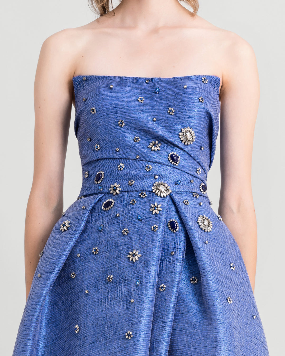 A close-up of a strapless draped blue evening dress with beadings.