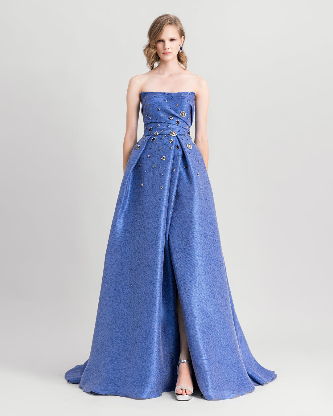 A strapless draped blue evening dress with beadings and an open slit on the side.