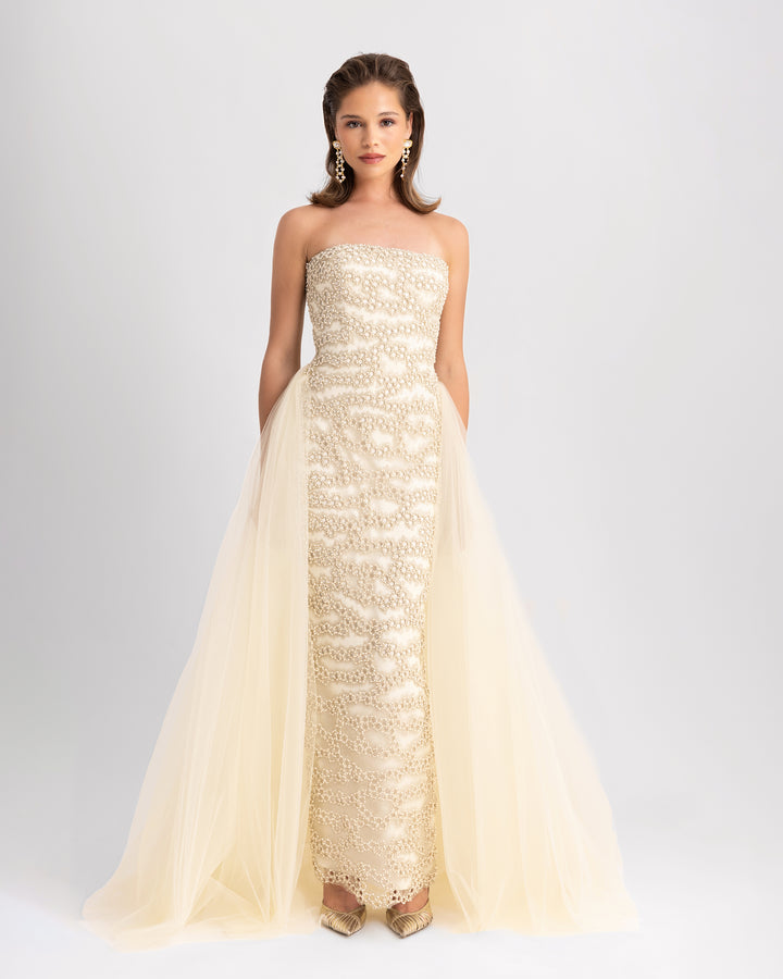 A strapless, fully embroidered slim-cut evening dress in cream, with a flowy tulle tail.