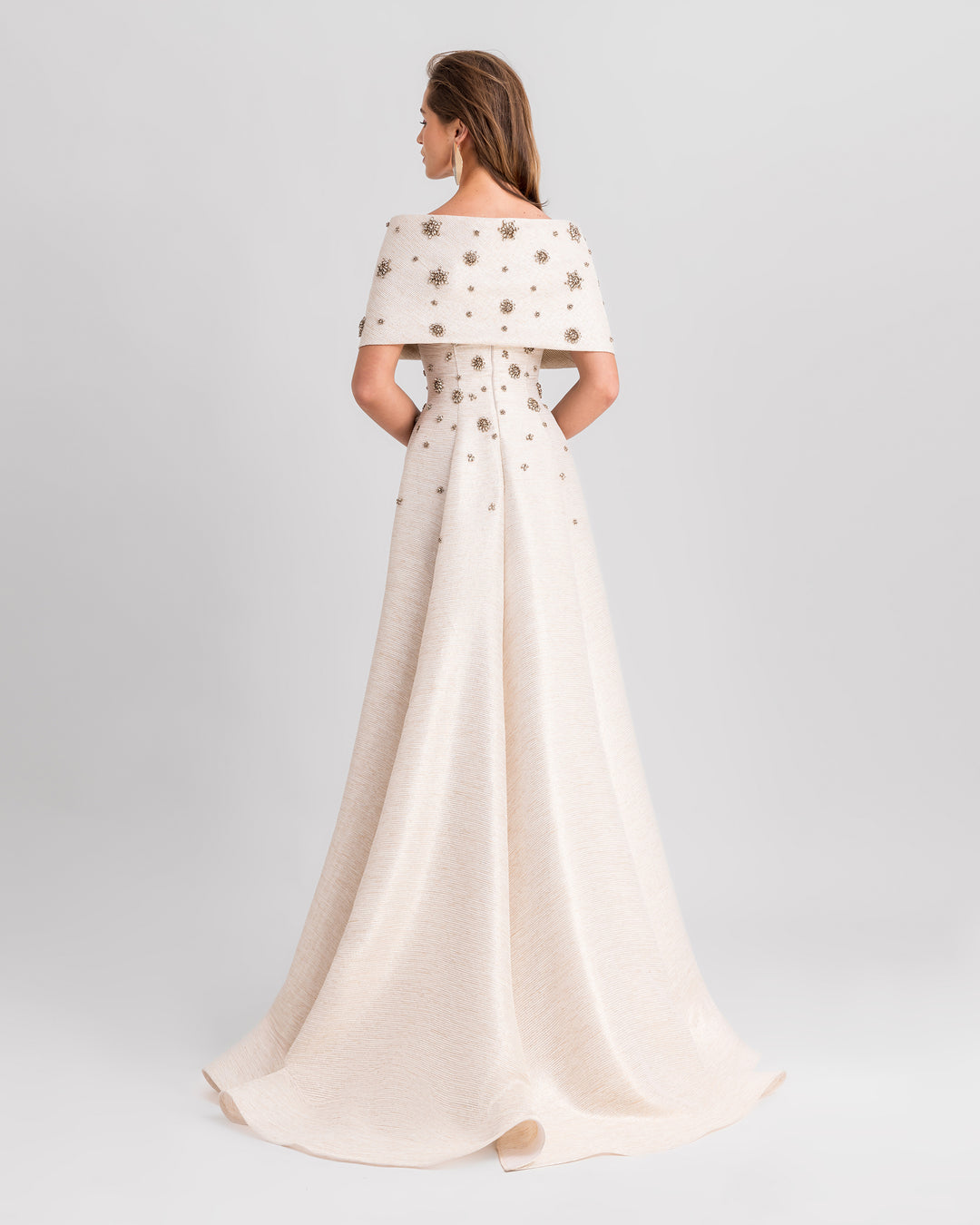 The back of an off-the-shoulders cream evening dress with beadings, and a draped skirt