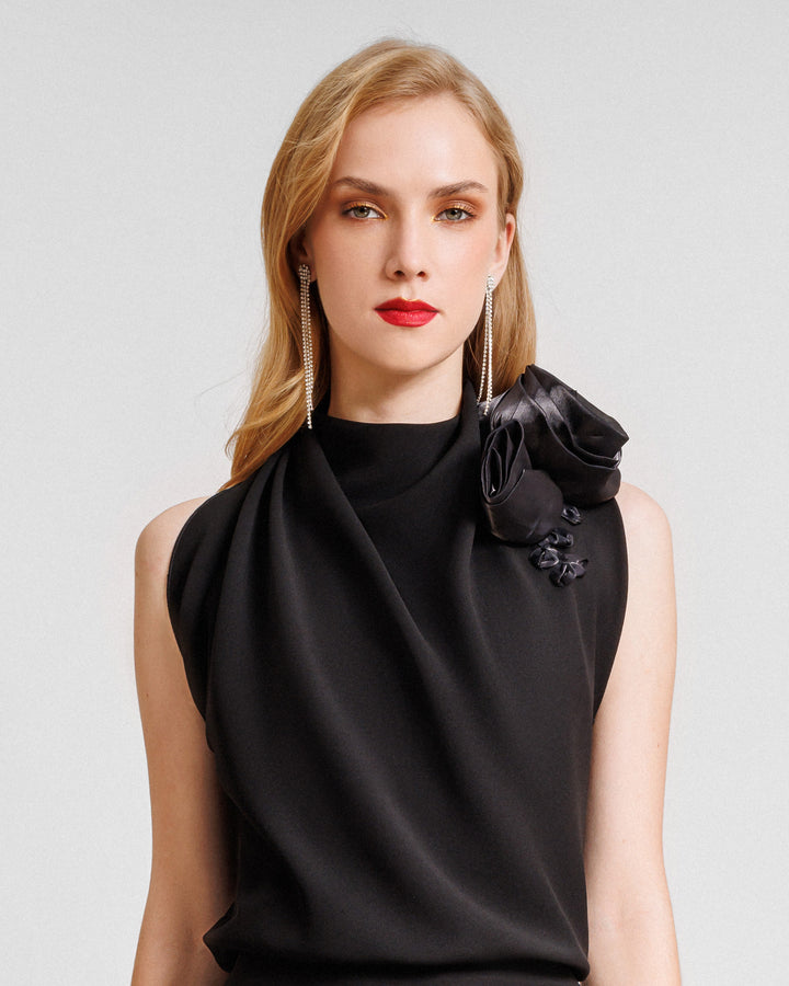 A draped loose black top with draped florals on the shoulders.