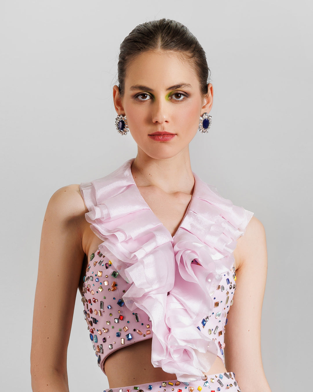 A close-up of a pink evening wear set featuring a fully beaded top with a detachable ruffled neckline.