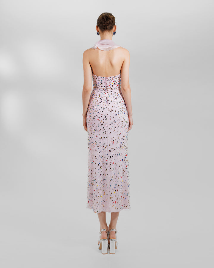 The back of a pink evening wear set featuring a fully beaded top with a detachable ruffled neckline, paired with a fully beaded midi skirt.