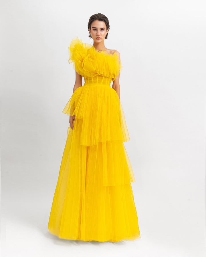 A yellow one-shoulder ruffled corset tulle dress with fully pleated wide skirt.