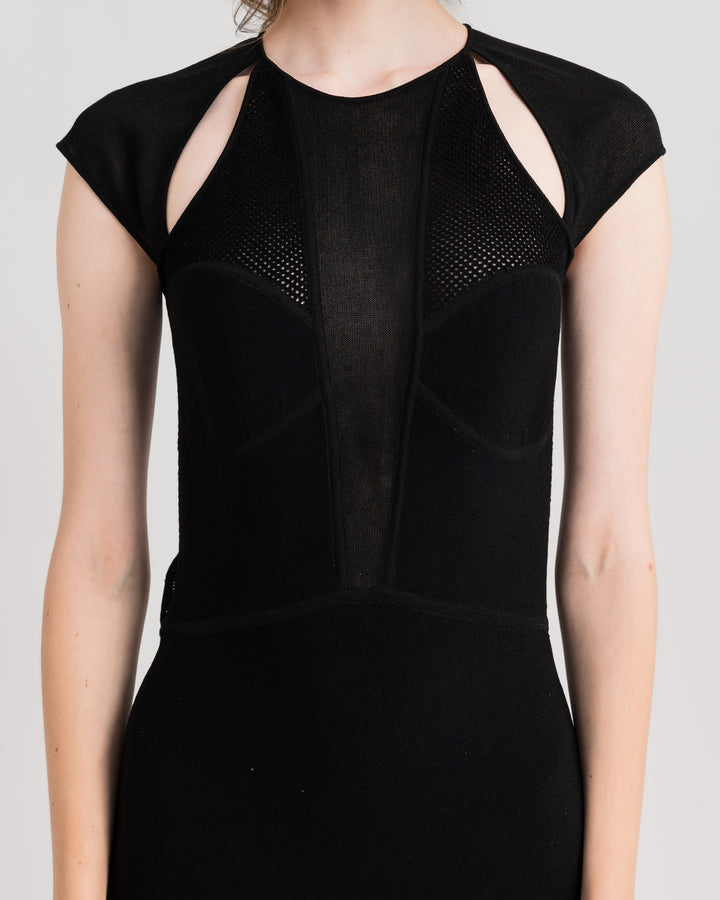 A close-up of a black flared midi knit dress featuring cut-outs on the shoulders an a long v-neckline.