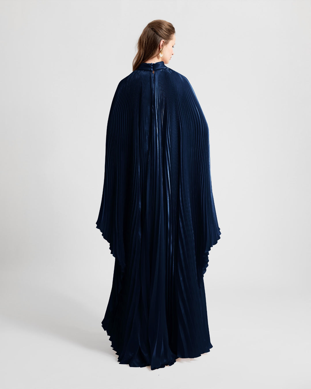 The back of a high neckline fully pleated flared navy organza dress with cape-like sleeves.