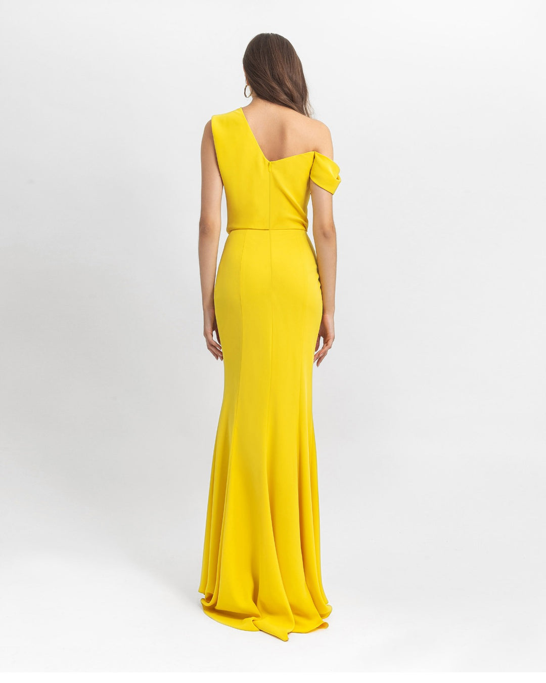 The back of an asymmetrical cut crepe long yellow evening dress with draping details on the upper part and a slim cut skirt.