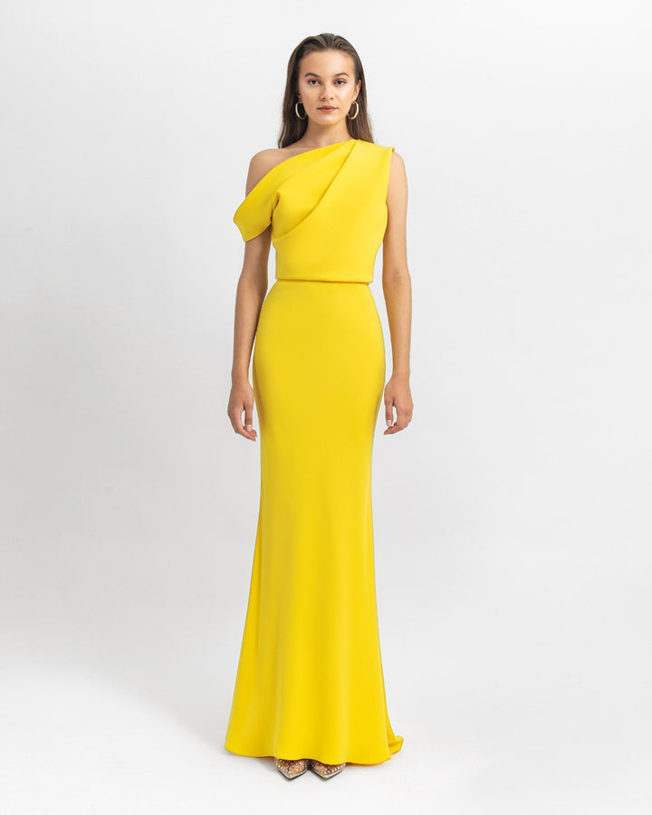 An asymmetrical cut crepe long yellow evening dress with draping details on the upper part and a slim cut skirt.