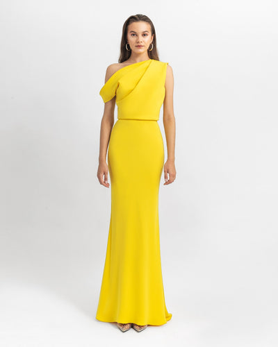 An asymmetrical cut crepe long yellow evening dress with draping details on the upper part and a slim cut skirt.