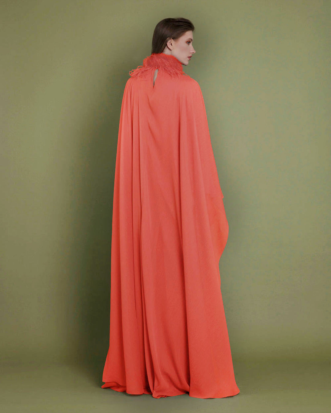 The back of a loose cut chiffon evening dress in orange color with cape-like sleeves, paired with a detachable feathered neckline.