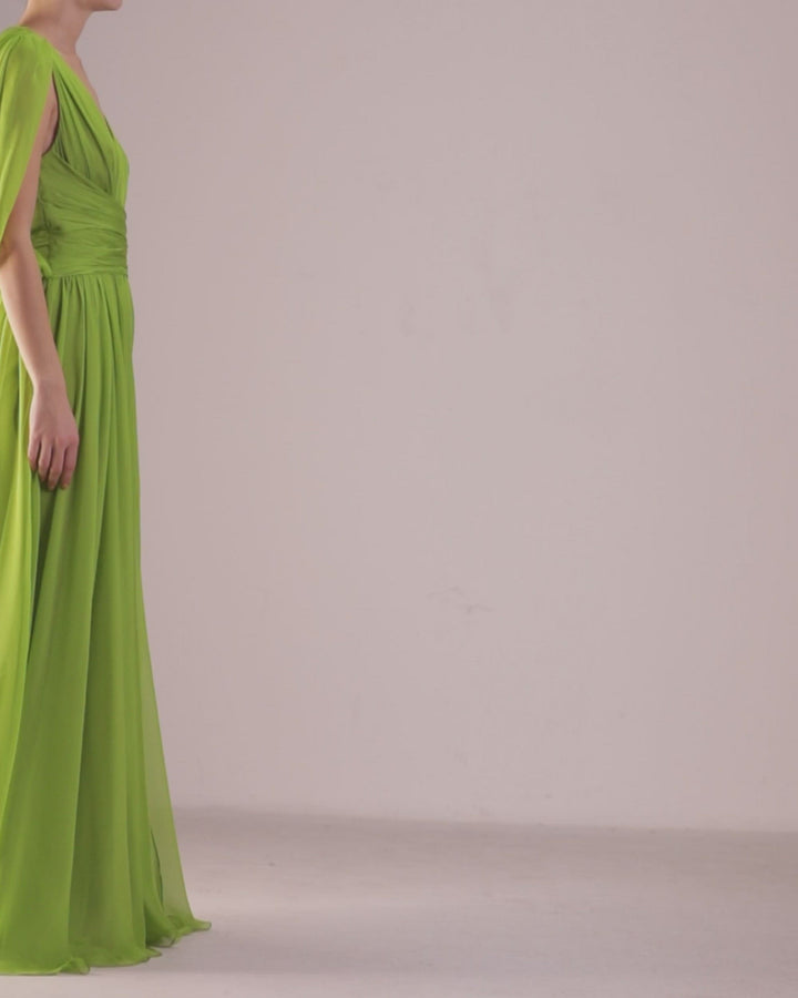 A deep V-neckline, green chiffon long evening dress with cape-like sleeves, draped details on the waist, and an open slit on the side.