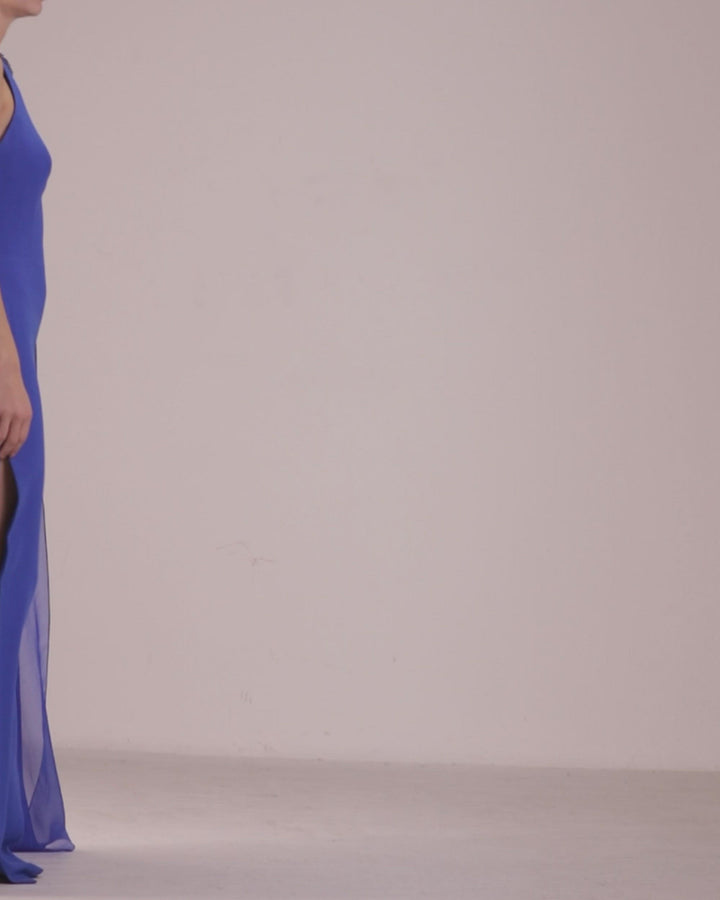 A rounded neckline, slim cut crepe blue dress with one sided draped flowy chiffon fabric and a side slit.