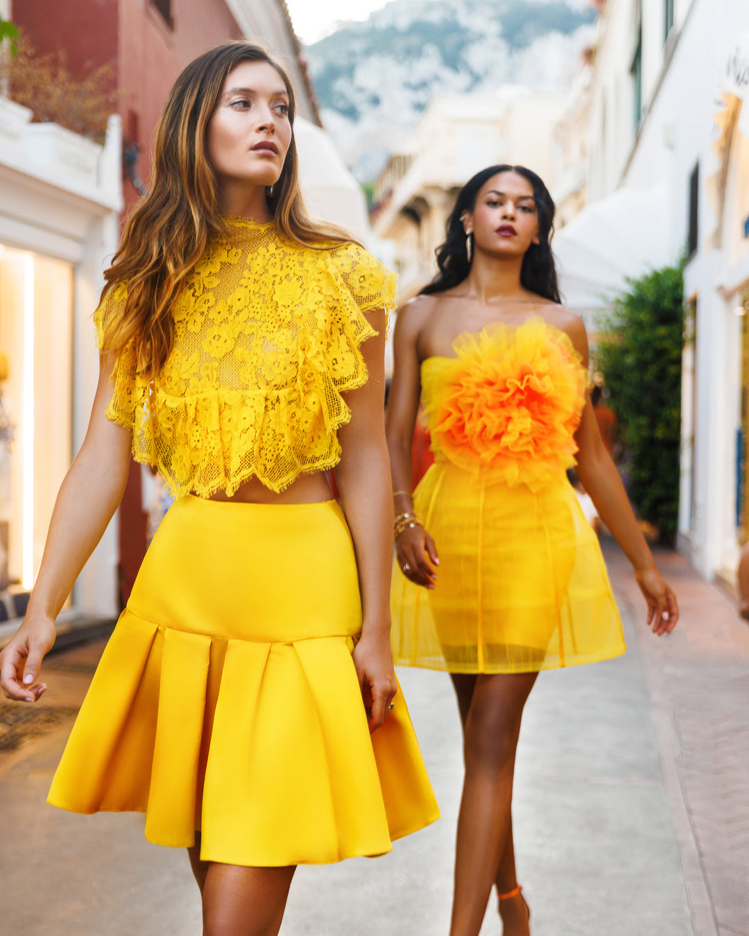 Two evening wear sets the first one featuring a lace top with a yellow satin mini skirt and the other one a gathered flower top paired with a cage mini skirt.