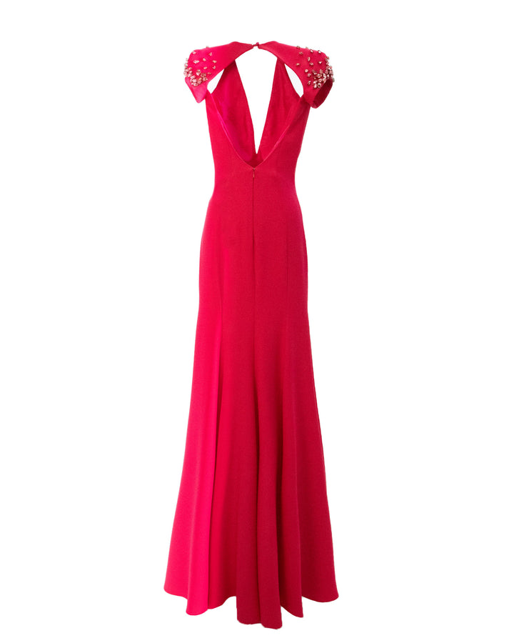 The back of a fuchsia long evening dress with a cut-out open back and embellished details on the shoulders.