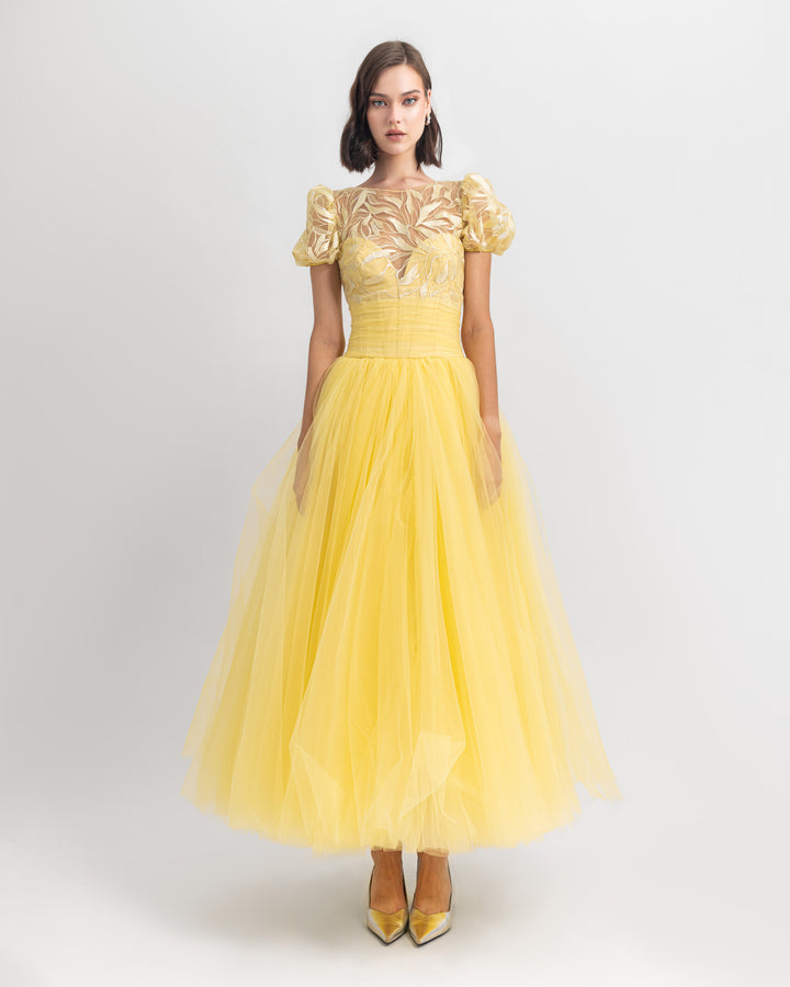 A heart shape corset with puffed sleeves intricated embroidery yellow midi dress and a wide cut tulle midi skirt.