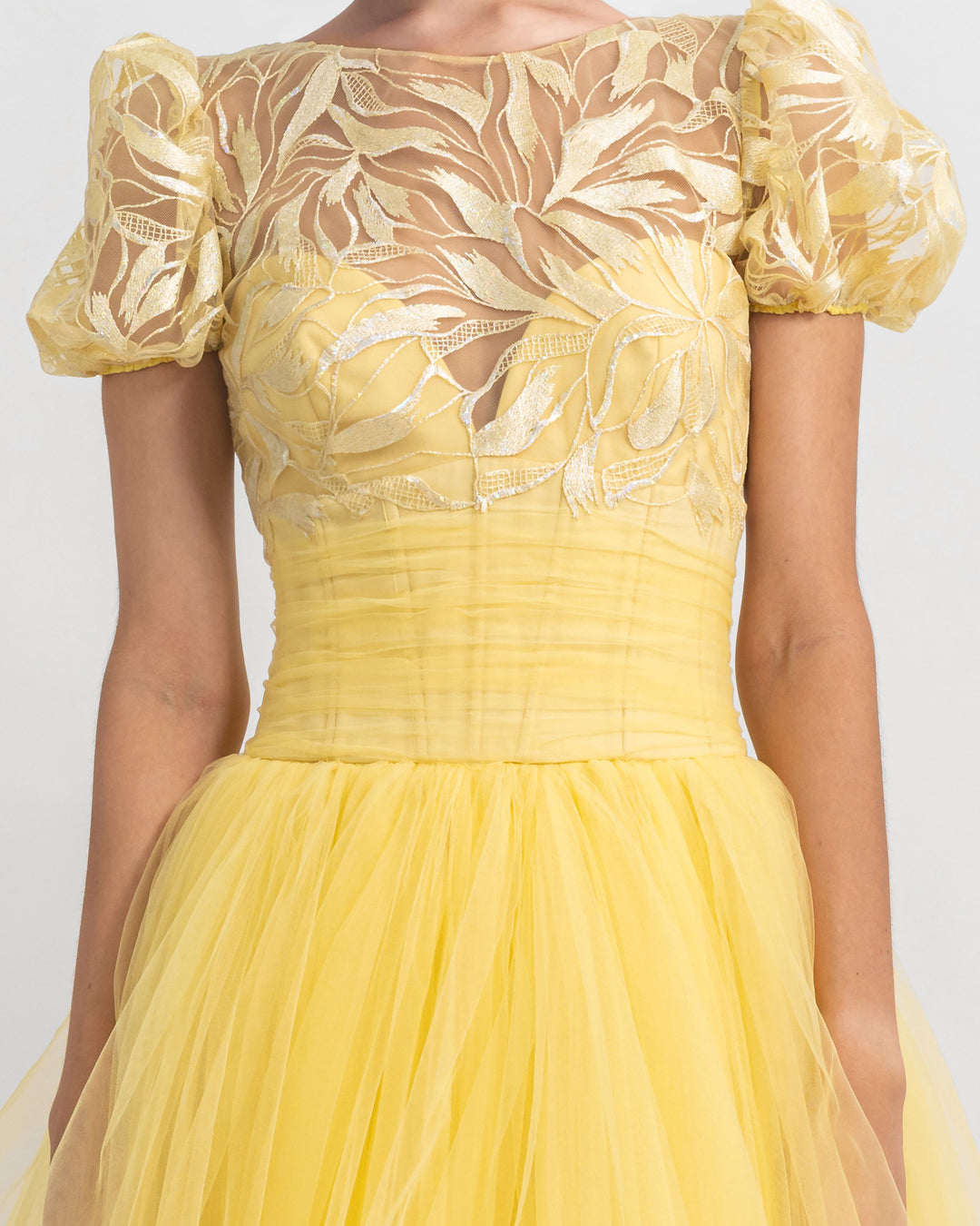 A close-up of a heart shape corset with puffed sleeves intricated embroidery evening dress in yellow.